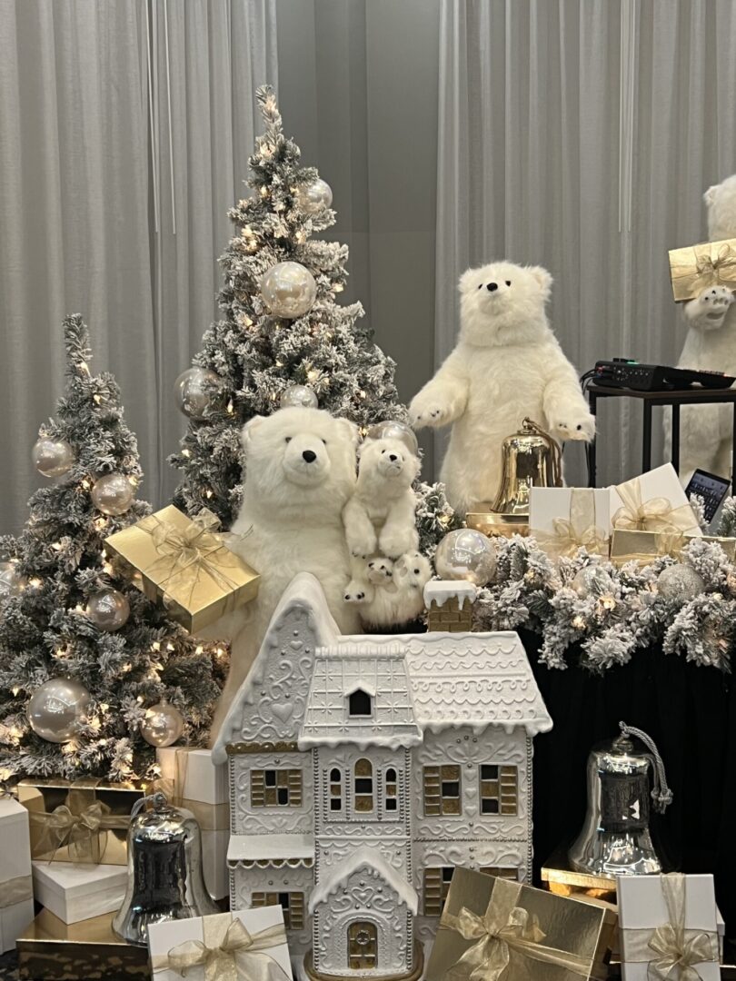 A group of white teddy bears sitting next to christmas trees.