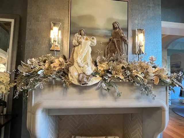 A fireplace mantle with statues and flowers on it