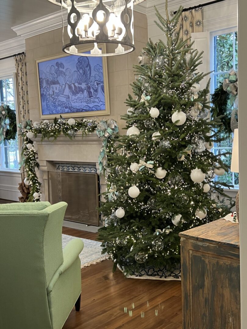 A christmas tree in the living room with white ornaments.